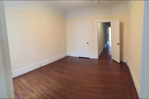 an empty living room with wood flooring and white walls